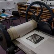 A person using a large printing press  Description automatically generated
