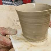 A person holding a clay pot  Description automatically generated