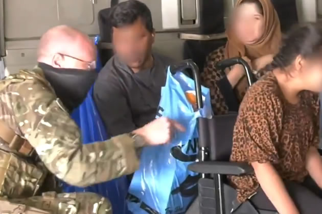 A British soldier helps an Afghan family on board a plane to the UK